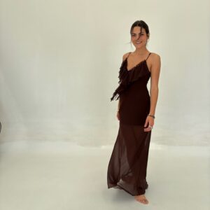 Vestido largo de gasa o tejido semi-transparente, con breteles finos y un escote en V pronunciado con volados. Silueta ajustada y fluida. Disponible en Marrón y Negro.