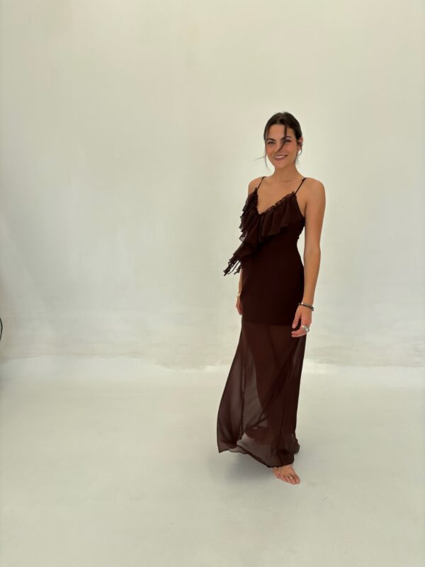 Vestido largo de gasa o tejido semi-transparente, con breteles finos y un escote en V pronunciado con volados. Silueta ajustada y fluida. Disponible en Marrón y Negro.