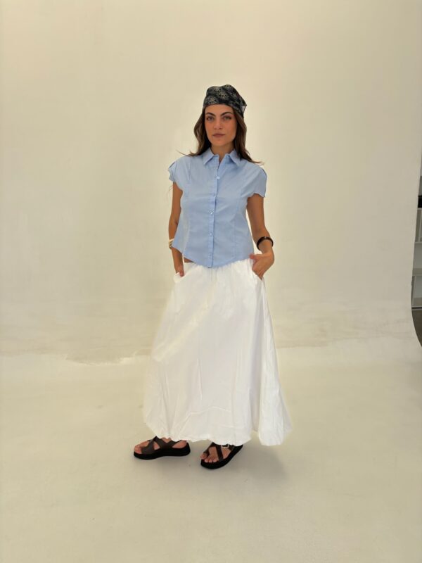 Camisa de poplin liso, manga corta, color liso (ej. negro/blanco). Diseño entallado con pinzas en los hombros.