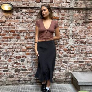 Pollera midi negra, de corte al bies (o A), con tejido de satén de acabado mate y caída fluida. Ideal para looks elegantes y minimalistas.