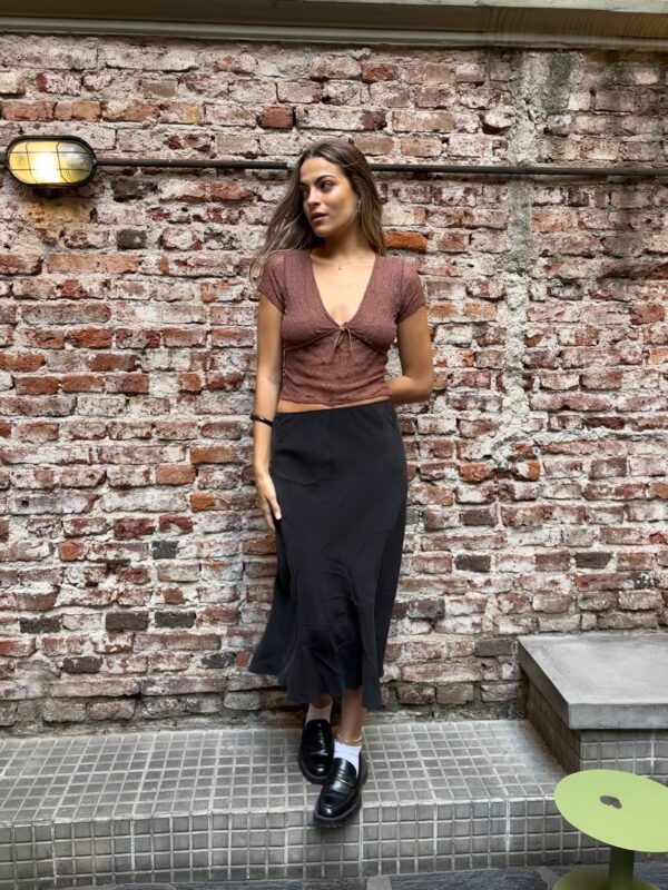 Pollera midi negra, de corte al bies (o A), con tejido de satén de acabado mate y caída fluida. Ideal para looks elegantes y minimalistas.