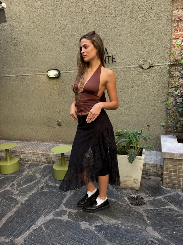 Pollera maxi asimétrica de cintura baja, confeccionada en encaje negro con estampado floral y volados irregulares en el ruedo. Transparente y de estilo bohemio.